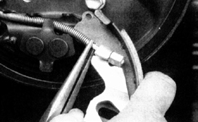 14. Переверните заднюю колодку и отведите пружину от рычага ручного тормоза.