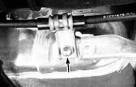 6. Открутите болт (указан стрелкой) крепления зажима тросика к панели пола.