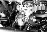 13. Работая сверху, отверните две гайки крепления (малая стрелка) патрубка к